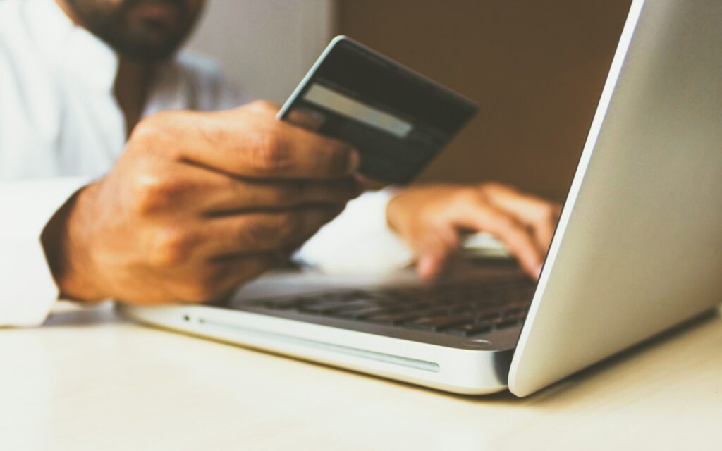 person using laptop computer holding card