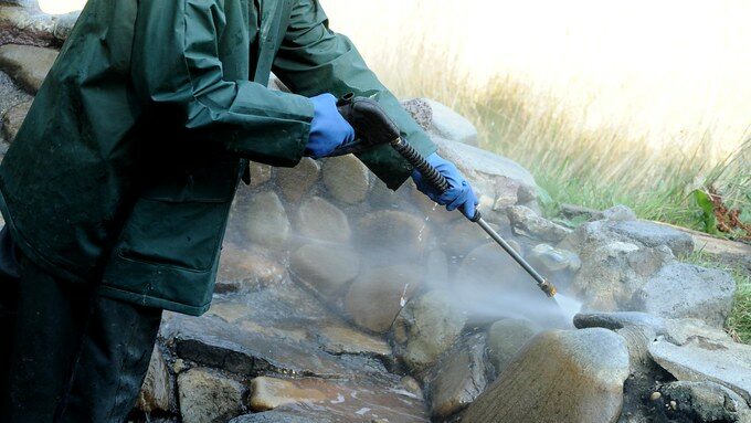 Man power washing a wall.