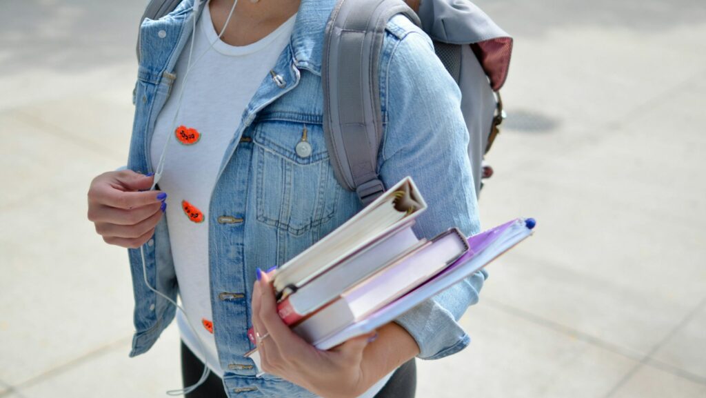 high school student wearing blue denim jacket holding book